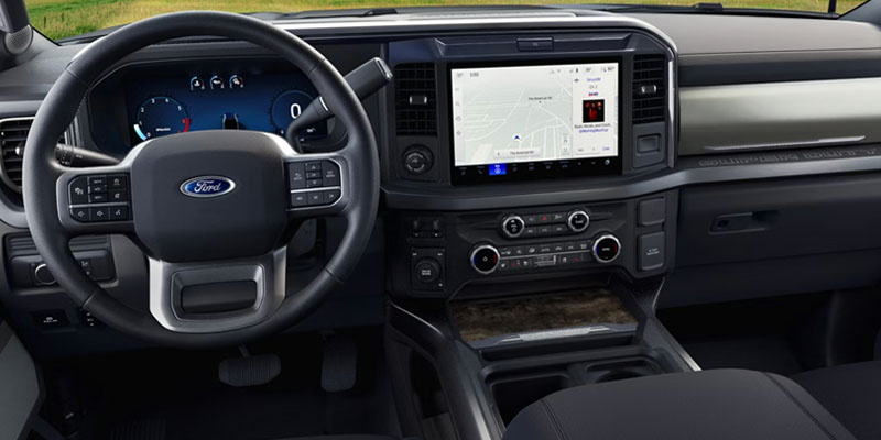 Interior view of a Ford vehicle, featuring a steering wheel with controls, a large touch screen displaying navigation, and climate control buttons