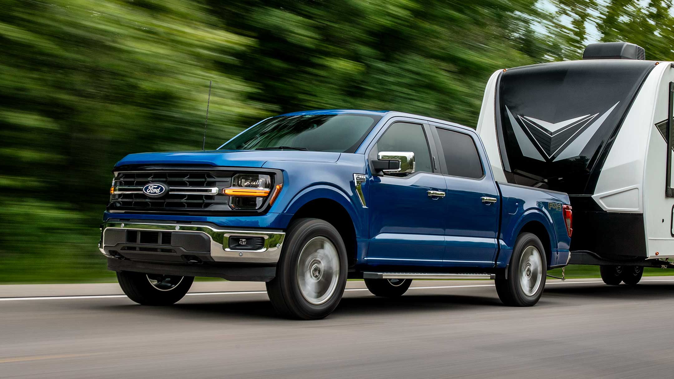 Blue Ford F-150 towing camper
